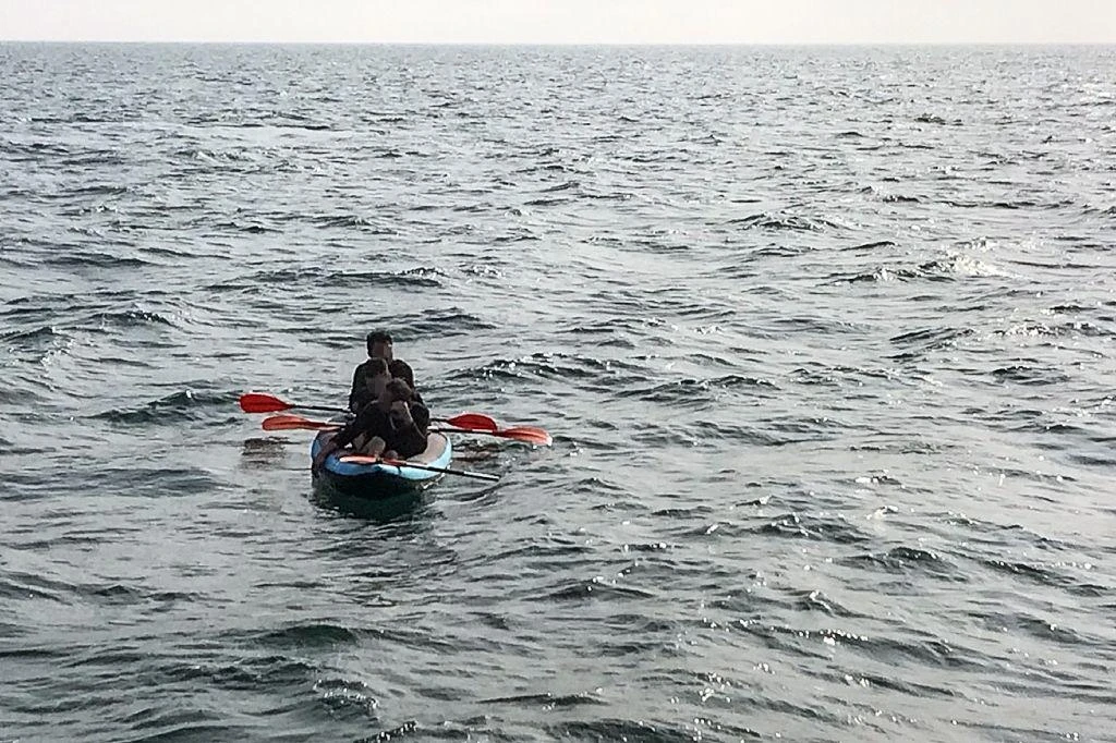 Three migrants, who were attempting to cross the English Channel from France to Britain, drift in an inflatable canoe off the French coast, near Calais, last year. (AFP)