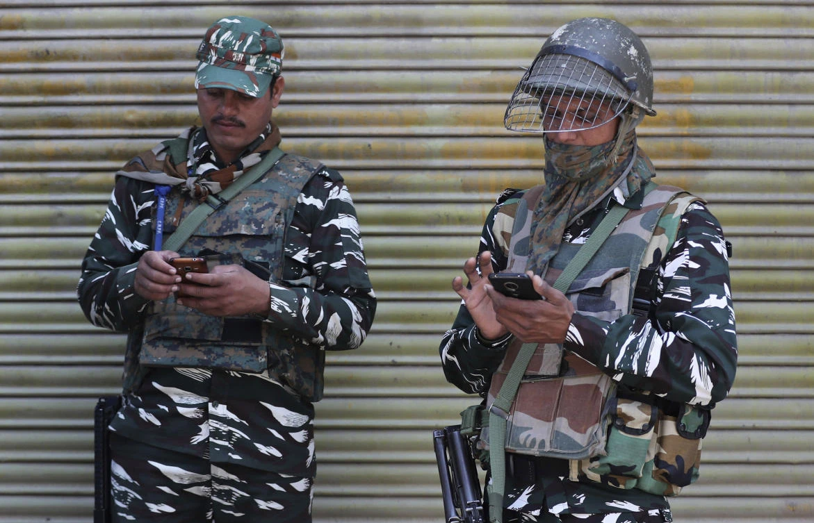 Indian paramilitary soldiers make calls from their cellphones as they guard a closed market in Srinagar, Indian controlled Kashmir, Monday, Oct. 14, 2019. (AP)