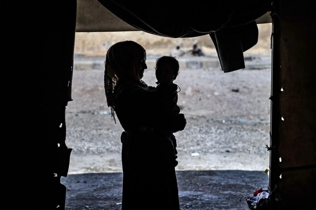 A volunteer attending an orphaned child reportedly linked with Daesh fighters in Syrian Ain Issa town. (File/AFP)