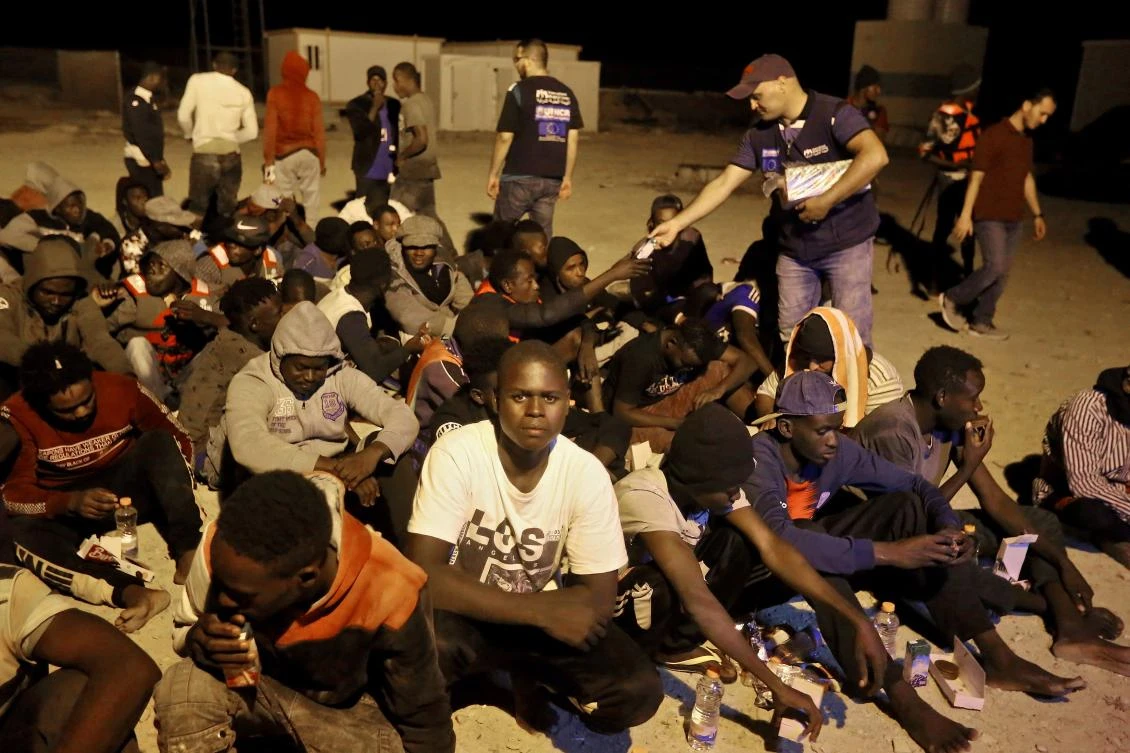Rescued African migrants sit late on October 16, 2019 by the coast in the Libyan town of Khoms, 120 kilometres (75 miles) east of the capital Tripoli, after being rescued from the Mediterranean Sea. (File/AFP/Mahmud Turkia)