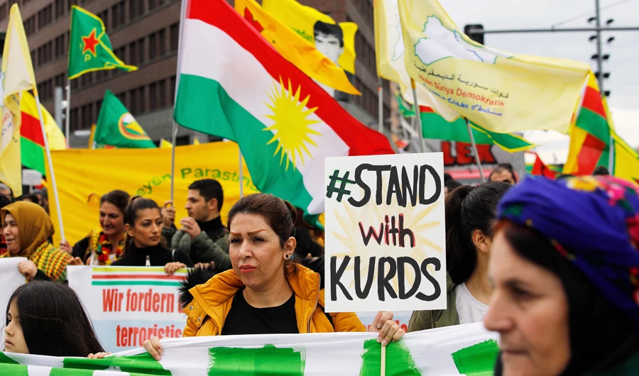 Kurdish protesters and their supporters hold up placards and wave flags during a demonstration against Turkey's military intervention in northern Syria in Berlin, on October 19, 2019. (AFP)