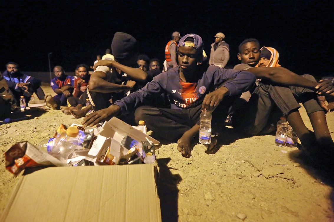 Rescued African migrants sit late on October 16, 2019 by the coast in the Libyan town of Khoms, 120 kilometres (75 miles) east of the capital Tripoli, after being rescued from the Mediterranean Sea. (AFP)