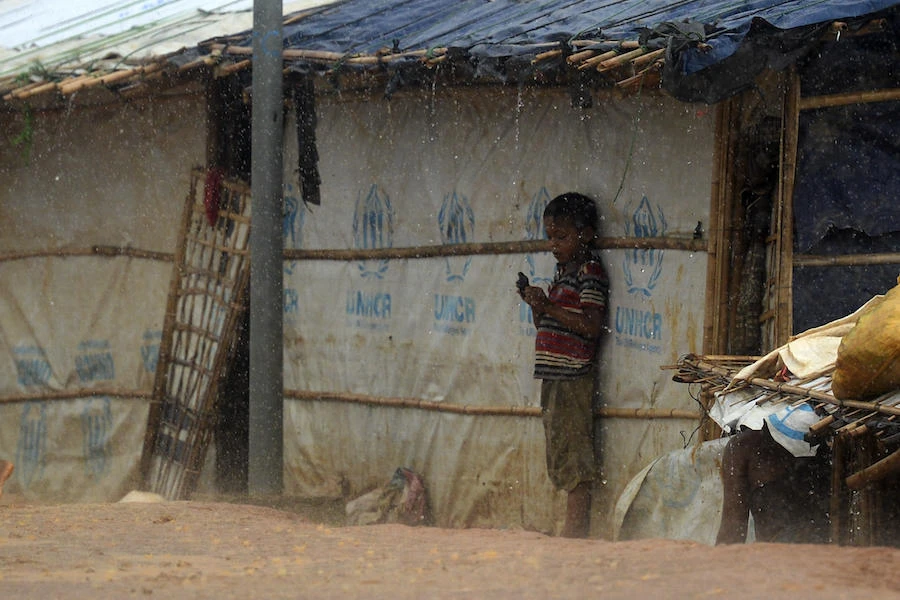A Rohingya refugee boy takes shelter during a rainfall at the Kutupalong Rohingya refugee camp in Bangladesh's Ukhia district on August 24, 2019. (AFP)