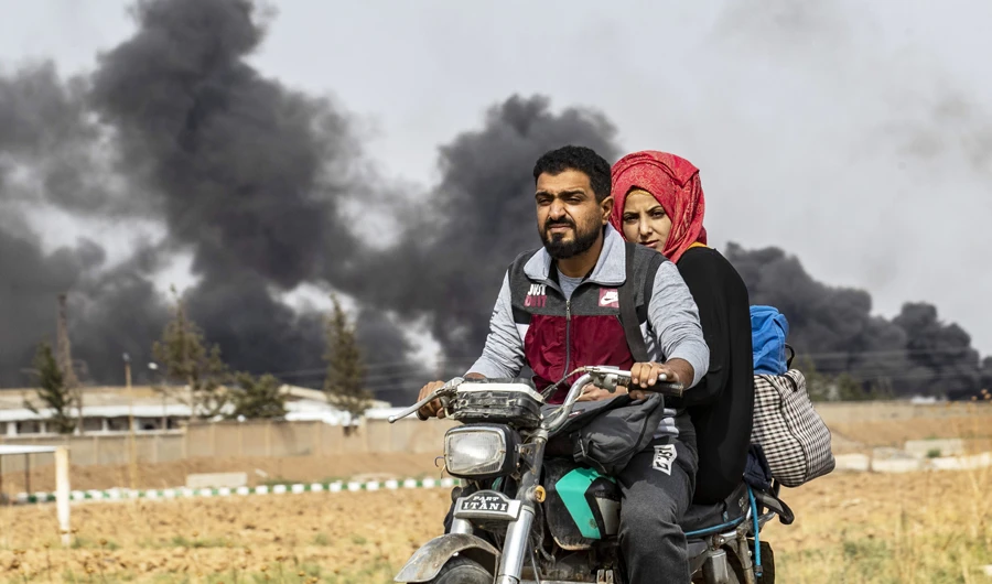 A Syrian couple use a motorcycle to flee the countryside of the northeastern Syrian town of Ras al-Ain on the Turkish border, toward the west to the town of Tal Tamr on October 19, 2019. (AFP)