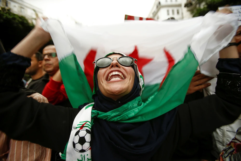 A demonstrator chants slogans and carry a national flag during a protest against the country's ruling elite and rejecting a December presidential election in Algiers. (Reuters)