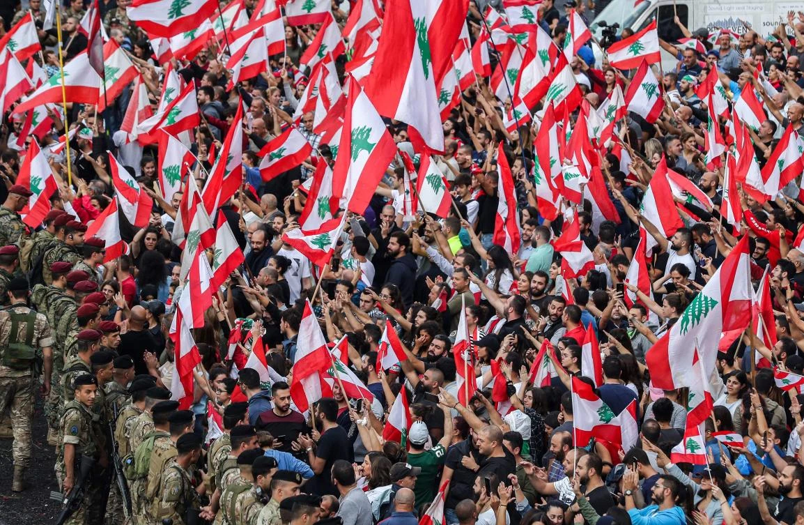 Protesters stand with Lebanese national flags before Lebanese army soldiers along the side of the Beirut-Jounieh highway in the northern Beirut suburb of Jal El-Dib on October 23, 2019. (AFP)