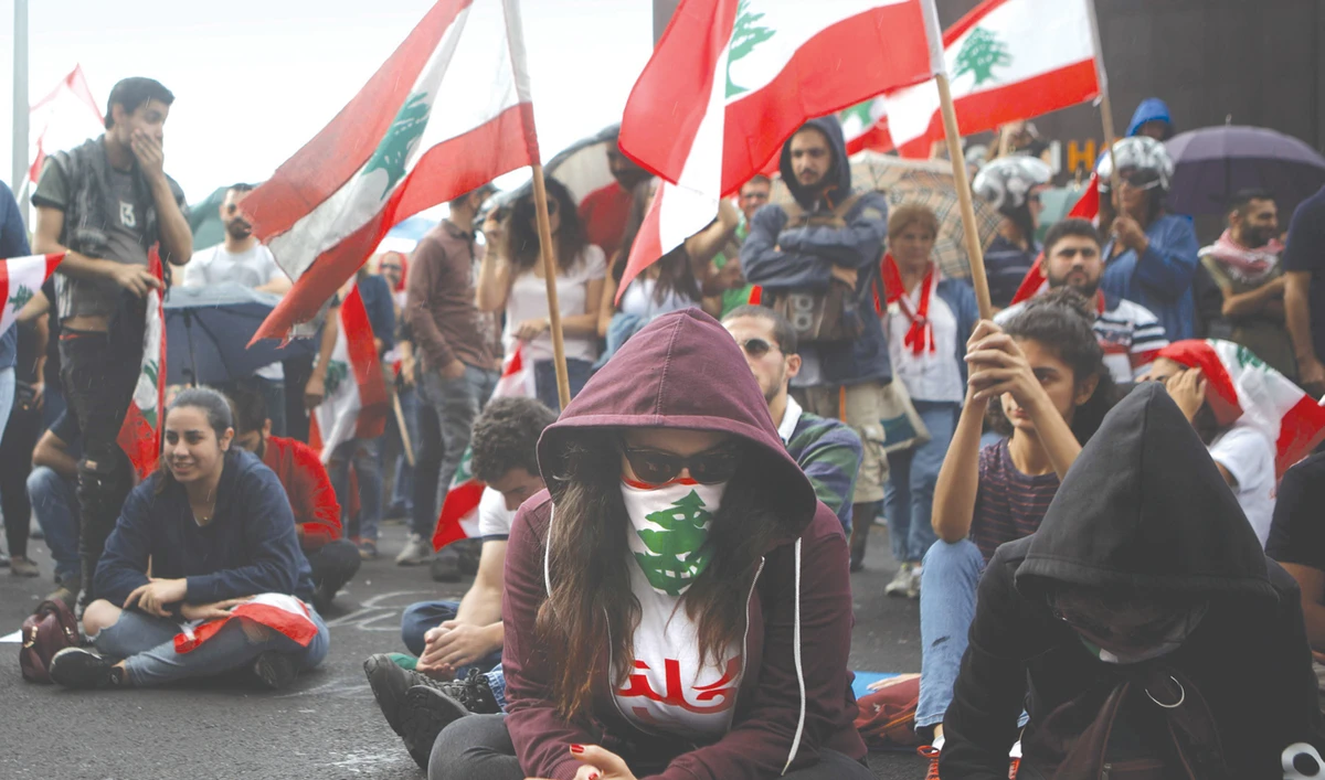 Lebanese protesters listen to a broadcast by their president in the town of Jal Al Dib, northeast of Beirut, on Thursday as demonstrations continue. (AFP)