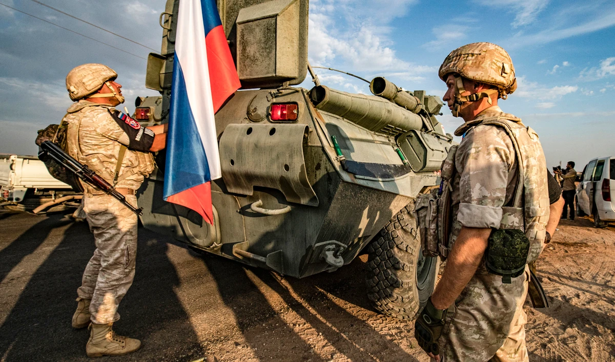 Russian military police members stand outside an armoured vehicle along a road in the countryside near the northeastern Syrian town of Amuda in Hasakeh province. (AFP)