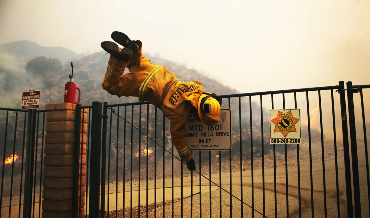 Fire firefighter hops over a locked gate while working the Tick Fire on October 24, 2019 in Canyon Country, California. (Getty Images/AFP)