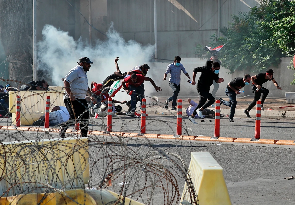 Anti-government protesters run for cover while Iraqi security forces fire tear gas during a demonstration in central Baghdad, Iraq, Friday, Oct. 25, 2019. (AP)