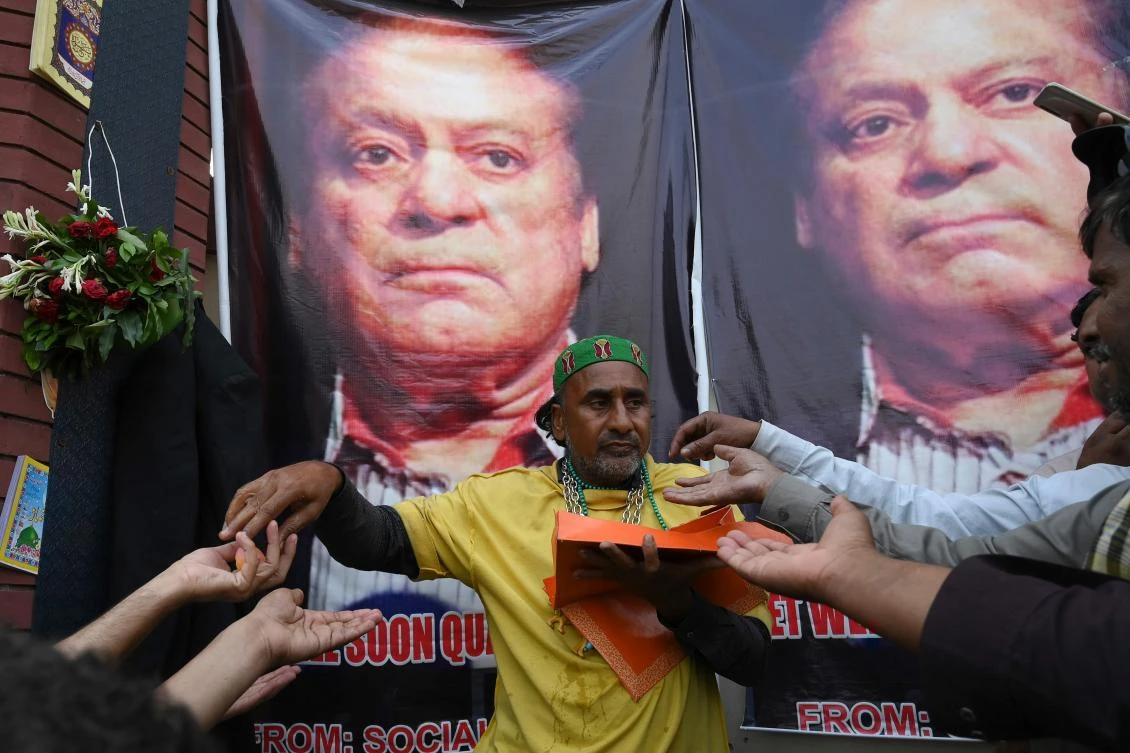 A supporter of Pakistan former Prime Minister Nawaz Sharif distributes sweets after the High court bailed Sharif on medical grounds, outside a hospital, in Lahore on October 25, 2019. (AFP)
