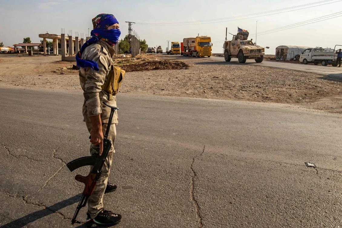 A Syrian Democratic Forces fighter stands guard as a convoy of US military vehicles passes through the Syrian northeastern city of Qamishli on Saturday, October 26, 2019. (AFP)