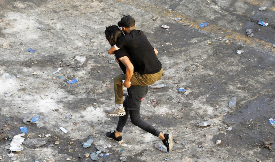 A demonstrator carries a boy during a protest in Baghdad on Sunday. (Reuters)