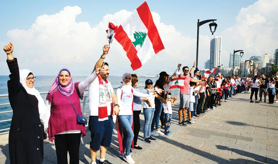Anti-government protesters form a human chain as a symbol of unity, during ongoing protests against the Lebanese government, on the Mediterranean waterfront promenade, in Beirut, on Sunday. (AP)