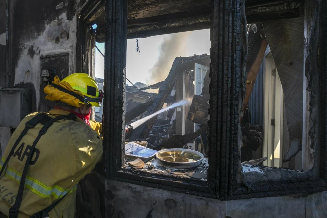 A firefighter hoses down a burning house during the Getty Fire on October 28, 2019 in Los Angeles, California. (File/AFP)