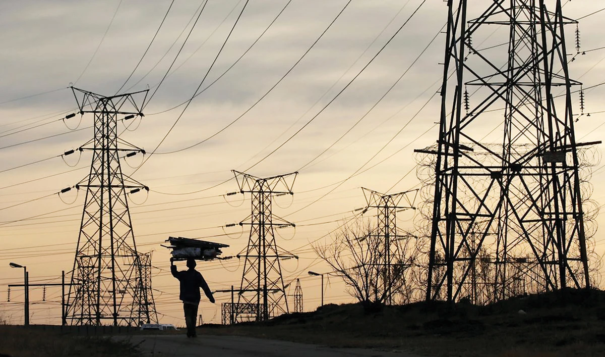 A woman carries firewood on her head as she walks below Eskom’s electricity pylons in Soweto, South Africa. (Reuters/File)