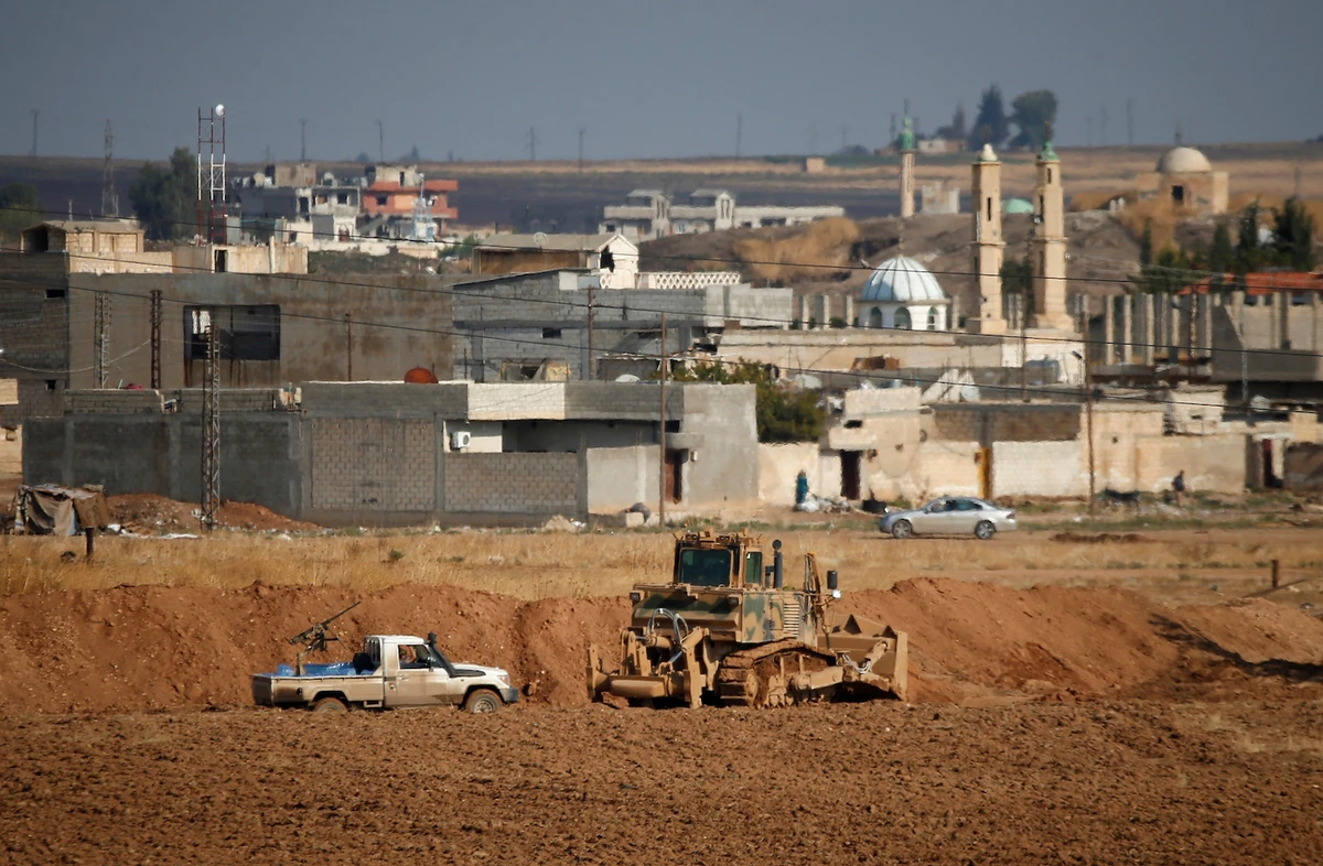A vehicle belonging to Turkey-backed Syrian rebel fighters is parked next to a Turkish military bulldozer in the Syrian town of Ras al Ain on October 30, 2019. (Reuters)
