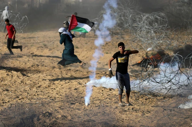 Palestinians react to tear gas fired by Israeli troops during a protest at the Israel-Gaza border, during which a Palestinian teenager was shot dead by Israeli soldiers. (Reuters)
