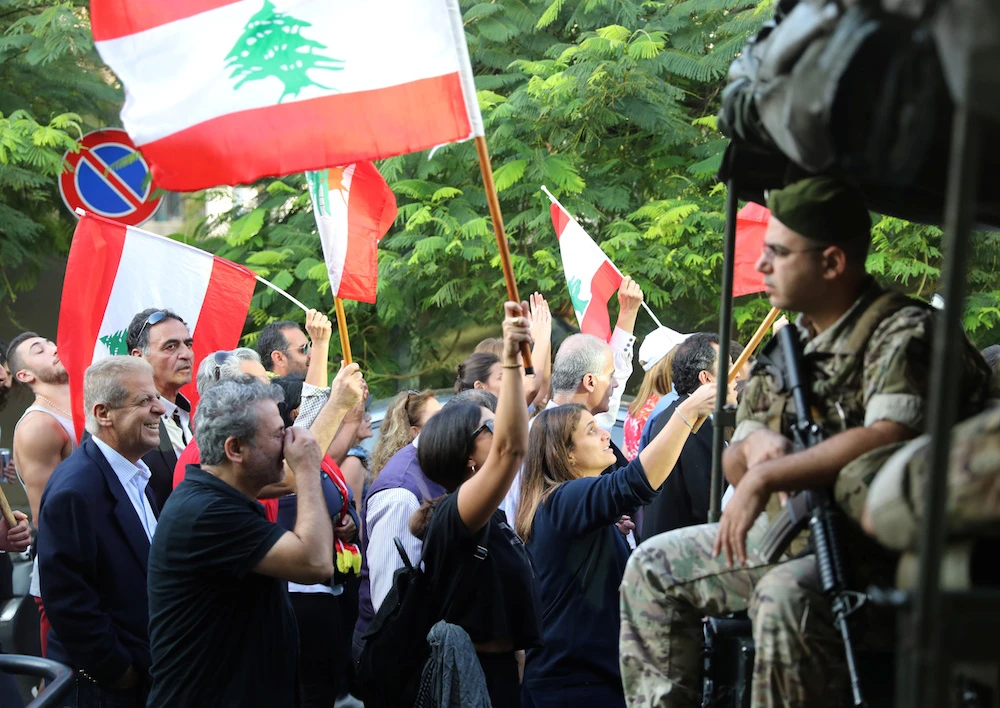 Demonstrators wave Lebanese flags as the pass by Lebanese soldiers during a protest in Beirut Thursday. (Reuters)