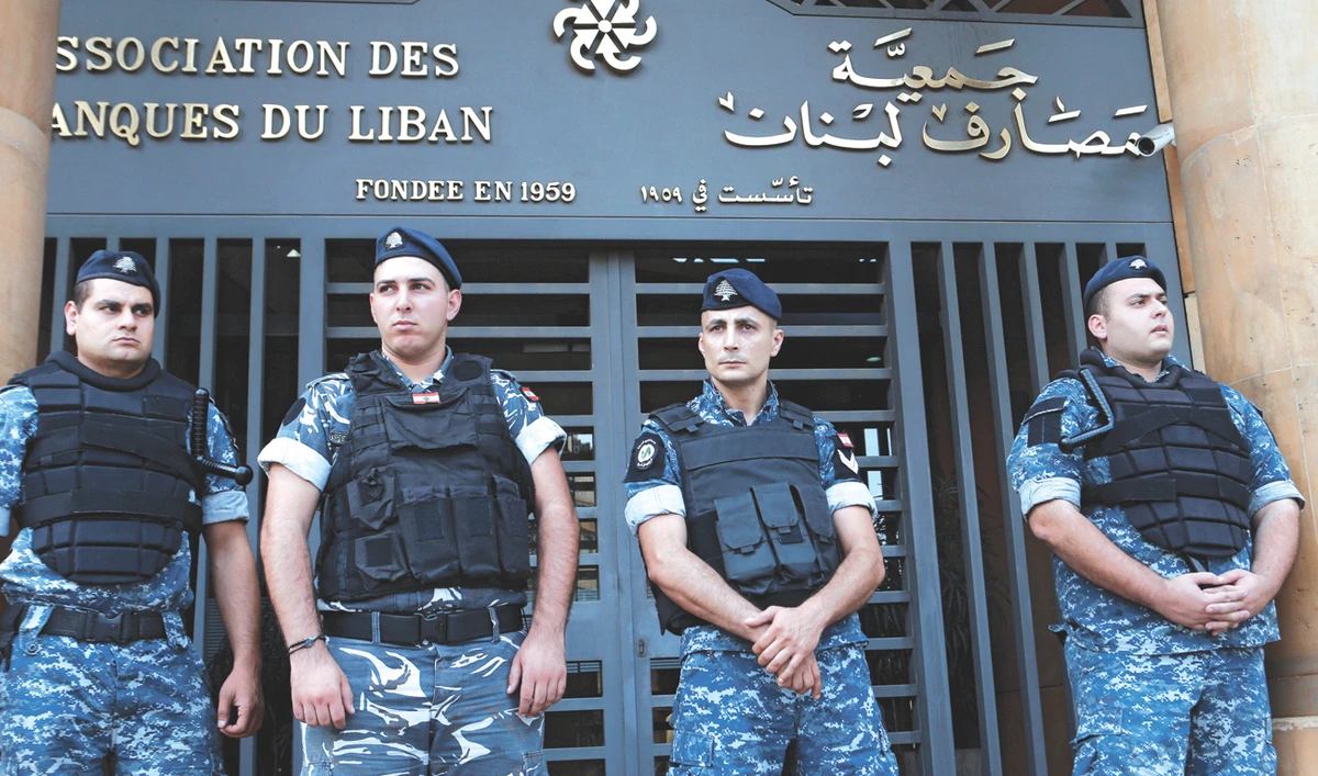 Lebanese police stand outside the entrance of the Association of Banks in Beirut as banks reopen after two weeks of closure due to ongoing protests. (Reuters)