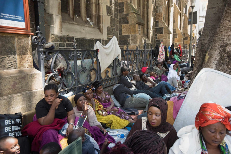 Hundreds of people originally from various countries are seen outside the Methodist Church where they have taken refuge after being chased away from a corridor close to the offices of the United Nations High Commission for Refugees(UNHCR) in Cape Town, on October 31, 2019. They are asking the UNHCR to intervene on their behalf. They say they don't feel safe in South Africa anymore due to high levels of crime as well as xenophobia. (AFP / RODGER BOSCH)