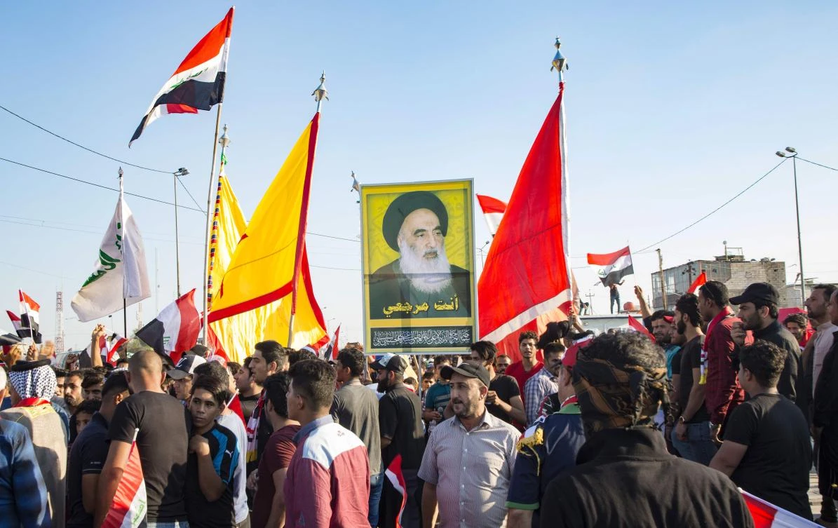 Iraqi demonstrators carry flags and an image of Shiite cleric Ayatollah Ali Husaini Al-Sistani, during ongoing anti-government protests in the southern city of Basra on November 1, 2019. (AFP)