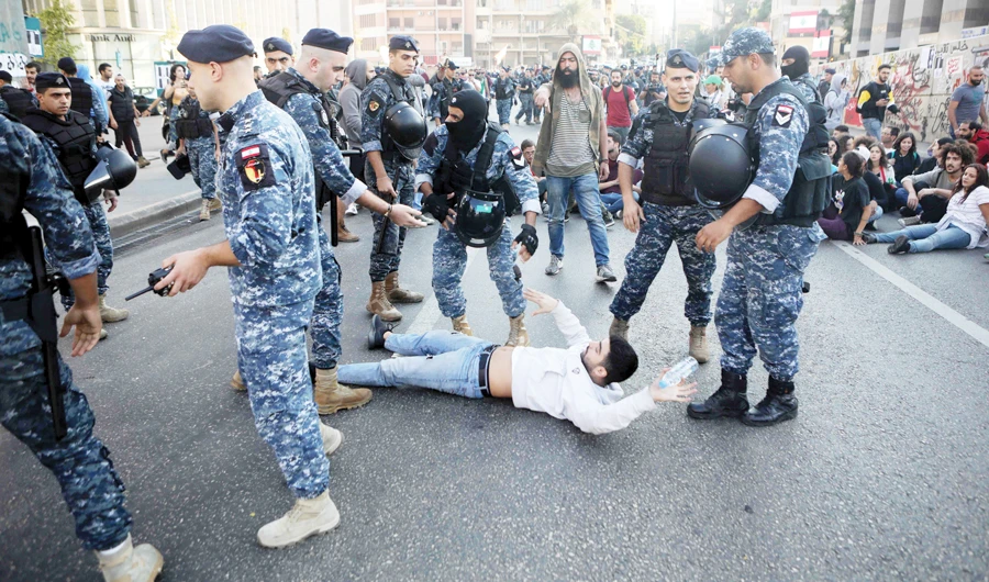Lebanese security forces try to remove unruly demonstrators blocking a road in a central neighborhood of capital Beirut on Monday. (AFP)