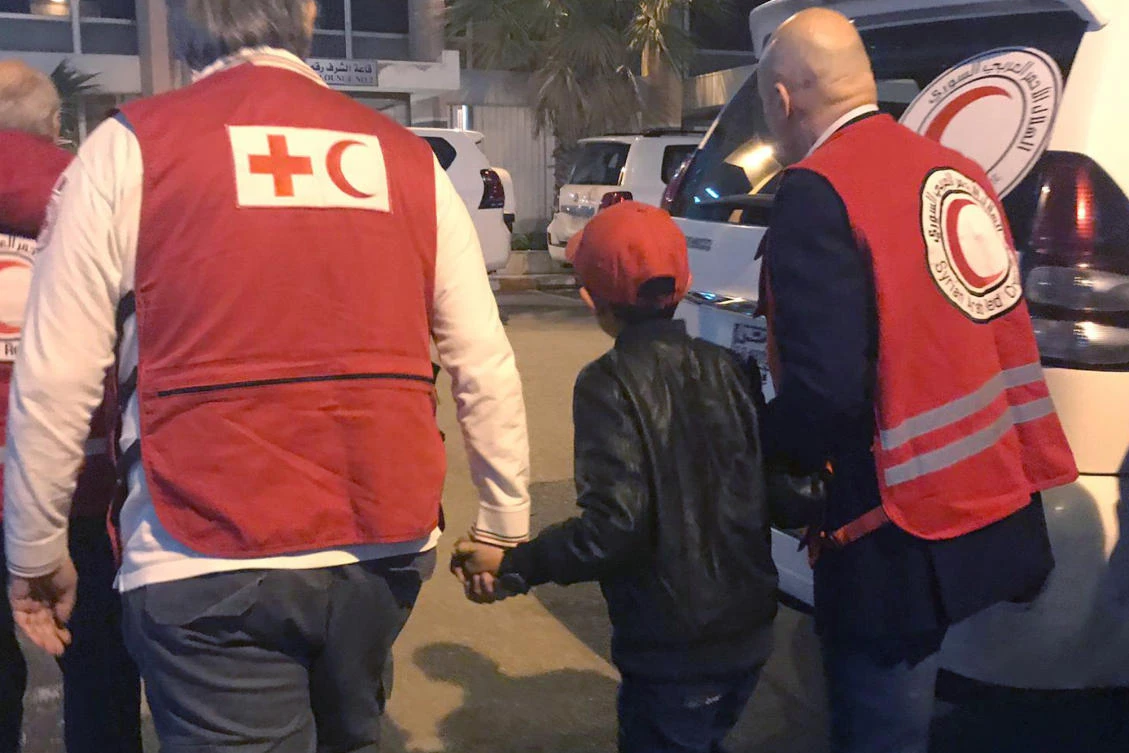 Alvin, an 11-year-old Albanian boy who was taken to Syria by his mother when she joined Daesh, is accompanied to Damascus airport by Red Cross and Red Crescent official. (AP)