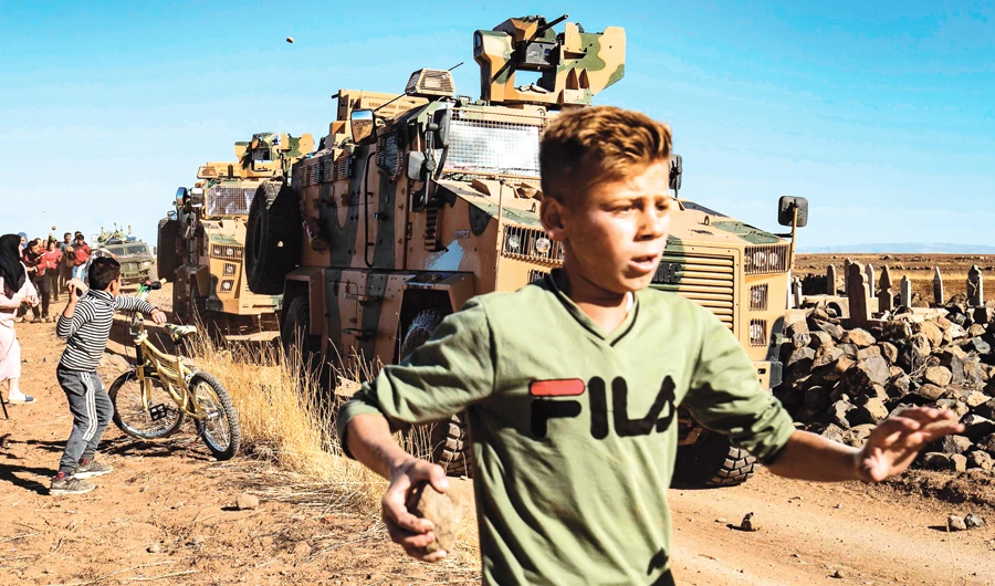 Kurdish demonstrators hurl rocks at a Turkish military vehicle on Friday, during a joint Turkish-Russian patrol near the town of Al-Muabbadah on the Syrian border with Turkey. (AFP)