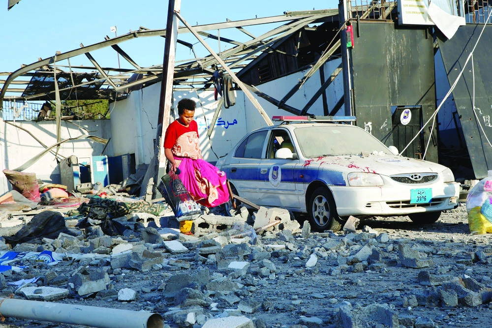 A migrant picks up clothes from among rubble at a detention center for mainly African migrants that was hit by an air strike in the Tajoura suburb of the Libyan capital of Tripoli on July 3, 2019. (REUTERS)