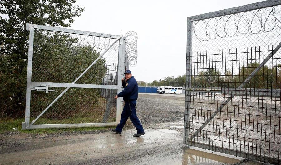 A member of Hungarian police closes a razor wired fence at a migrant transit center near Roszke, at the border crossing with Serbia on October 29, 2019. (AFP / OLIVER BUNIC)