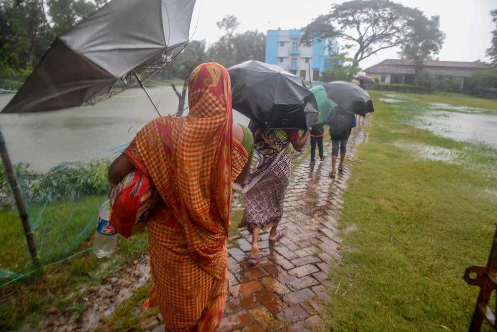 Villagers holding umbrellas carry their belongings on their way to enter a relief centre as Cyclone Bulbul is approaching, in Bakkhali near Namkhana in Indian state of West Bengal on November 9, 2019. (AFP / Dibyangshu Sarkar)