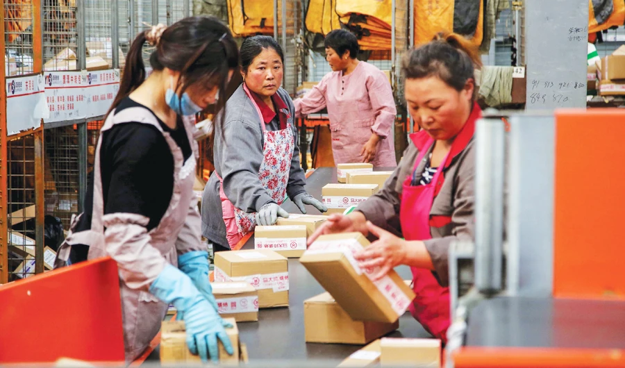 Workers sort packages at a logistics center in Lianyungang, China. Chinese manufacturers are facing continued pressure from existing tariffs. (AFP)