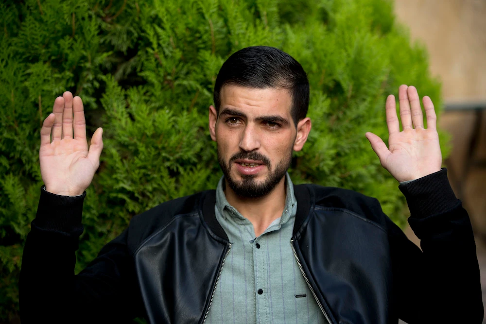 Palestinian Karam Qawasmi, who was shot in the back by Israeli forces in an incident caught on video last year, gestures as he gives an interview in the West Bank city of Hebron. (AP)