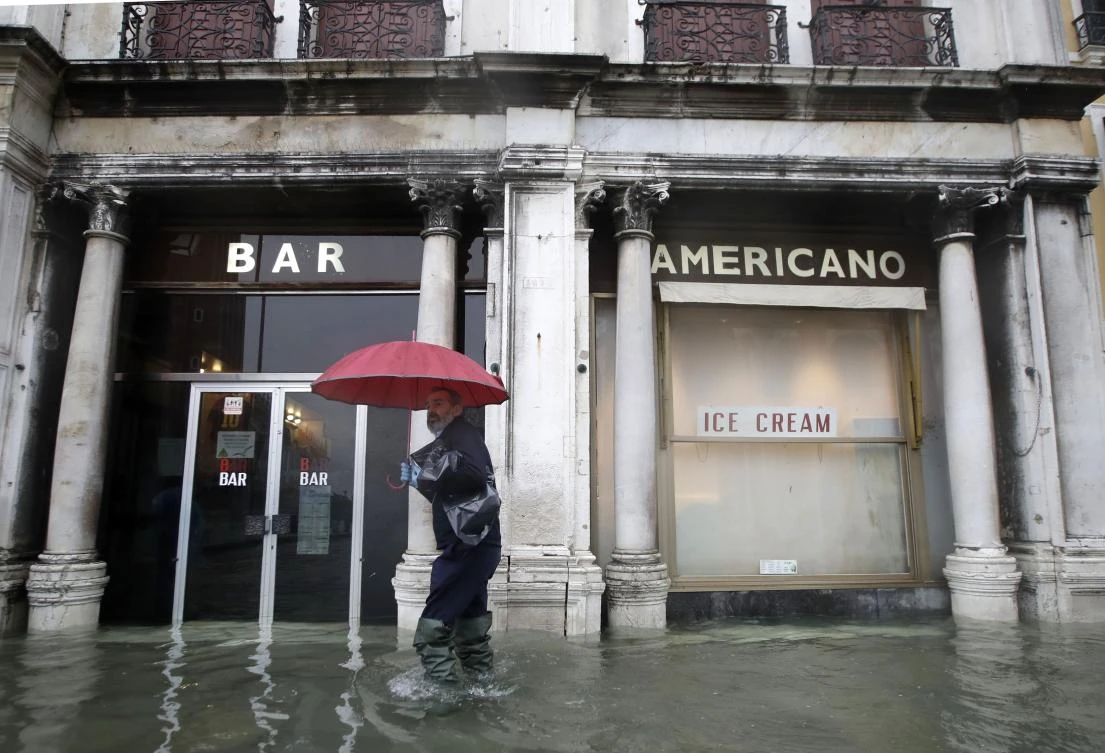 A man walks past a closed cafe in a flooded Venice, Italy, Tuesday, Nov. 12, 2019. (AP)