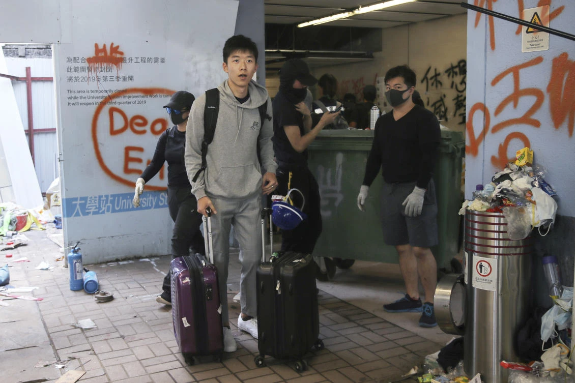 A student pushes his luggage past pro-democracy protesters as he leaves the Chinese University of Hong Kong following a clash in Hong Kong, Wednesday, Nov. 13, 2019. (AP)