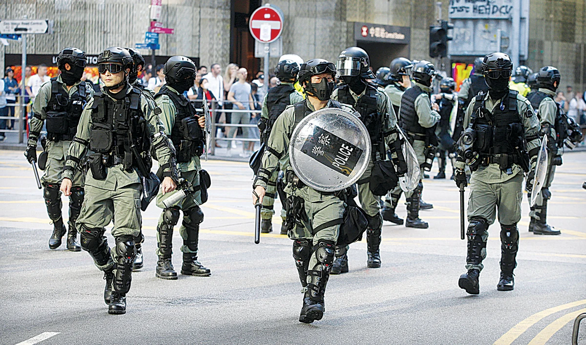 Police in riot gear arrive at the scene of a protest in the financial district in Hong Kong on Friday. Violent anti-government protests and the escalating US-China trade war have hit the financial hub. (AP)