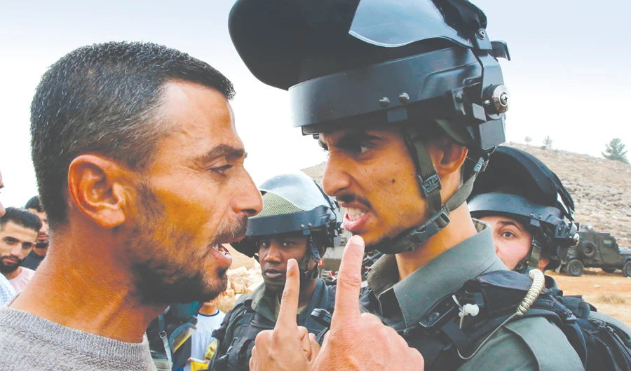 A Palestinian protester confronts an Israeli border policeman during a protest against the confiscation of lands in the village of Surif, northwest of the West Bank city of Hebron, on Friday. (AFP)