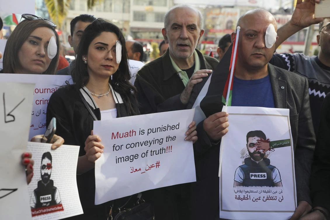 Palestinian journalists hold posters and wear eye patches as they rally in the West Bank city of Nablus on November 17, 2019, in solidarity with Palestinian cameraman Mu'ath Amarneh who days before was injured in his eye by a rubber bullet while covering clashes between Palestinian protesters and Israeli security forces in a West Bank demonstration. (AFP)