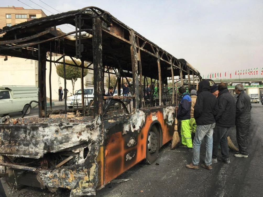 Residents inspect the wreckage of a bus that was set ablaze by protesters in the central city of Isfahan during a demonstration against a rise in gasoline prices on Sunday, November 17, 2019. (AFP)