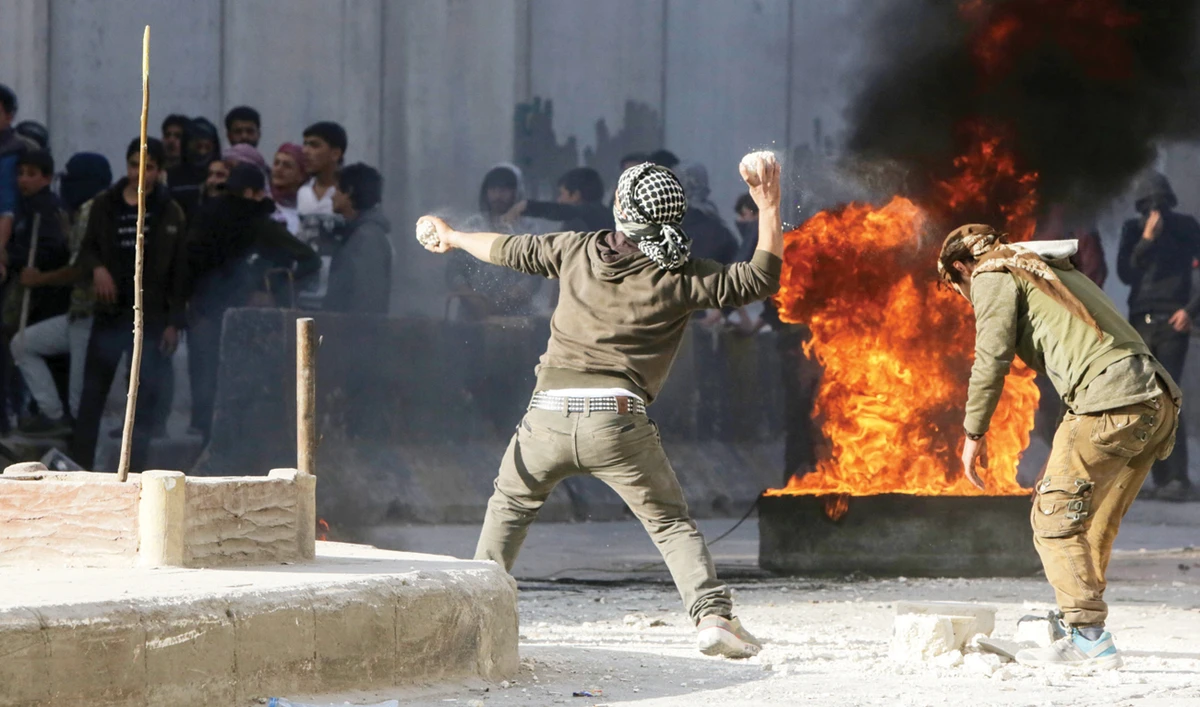 Protesters hurl stones at Turkish forces during a demonstration against Turkey’s presence in northern Syria. (AFP)