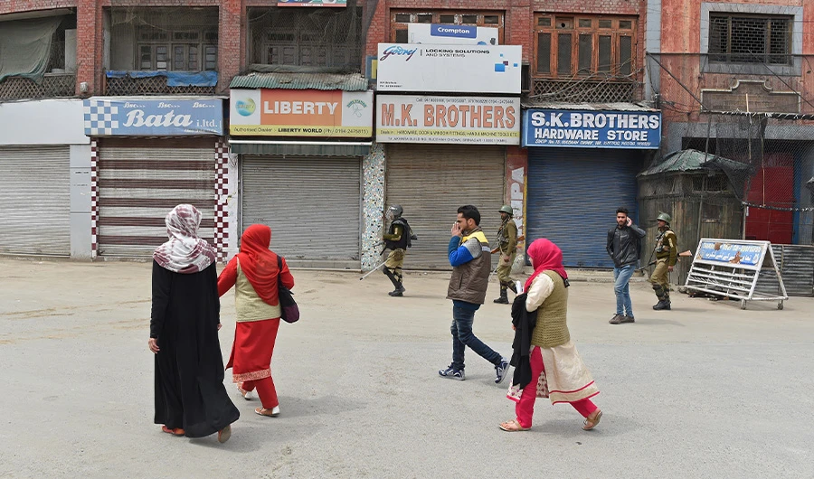 Kashmiri pedestrians walk by Indian paramilitary troopers patroling in Srinagar during a one-day strike called by Kashmiri separatists in Srinagar. (AFP)
