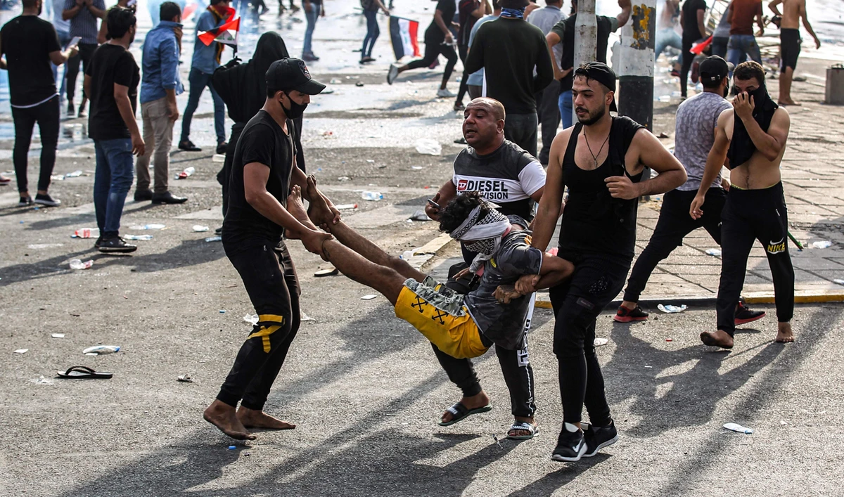 Iraqi protesters carry away an injured comrade amid clashes with riot police in Baghdad.