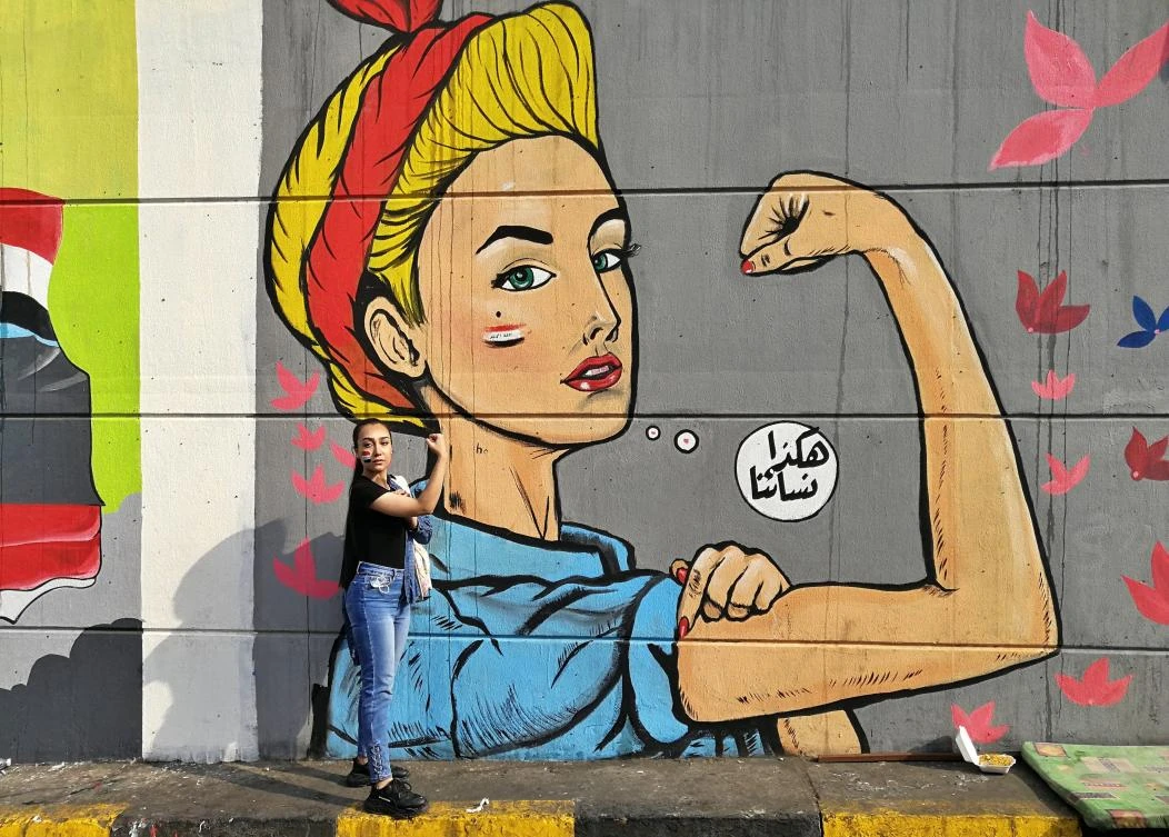 A woman poses for a photo in front of graffiti at the Saadoun tunnel, in Baghdad, Iraq. Nov. 18, 2019. (AP)