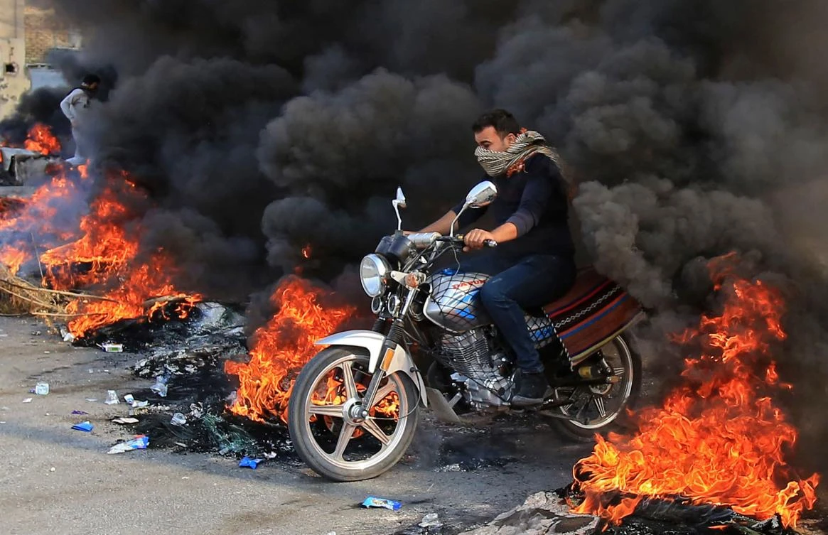 Thick columns of black smoke could still be seen rising from Karbala as demonstrators torched tires around and inside the city. (AFP)