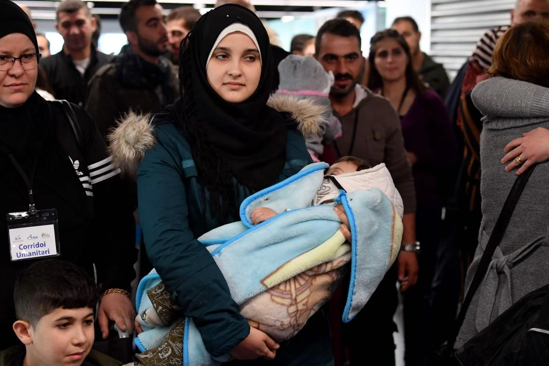 A Syrian woman carries a baby as Syrian refugees arrive at Rome's Fiumicino international airport on November 27, 2019 as part of a humanitarian corridor. 113 Syrian refugees from Lebanon-humanitarian corridors project of the Community of Sant'Egidio arrived on November 27 at Fiumicino airport. (AFP)