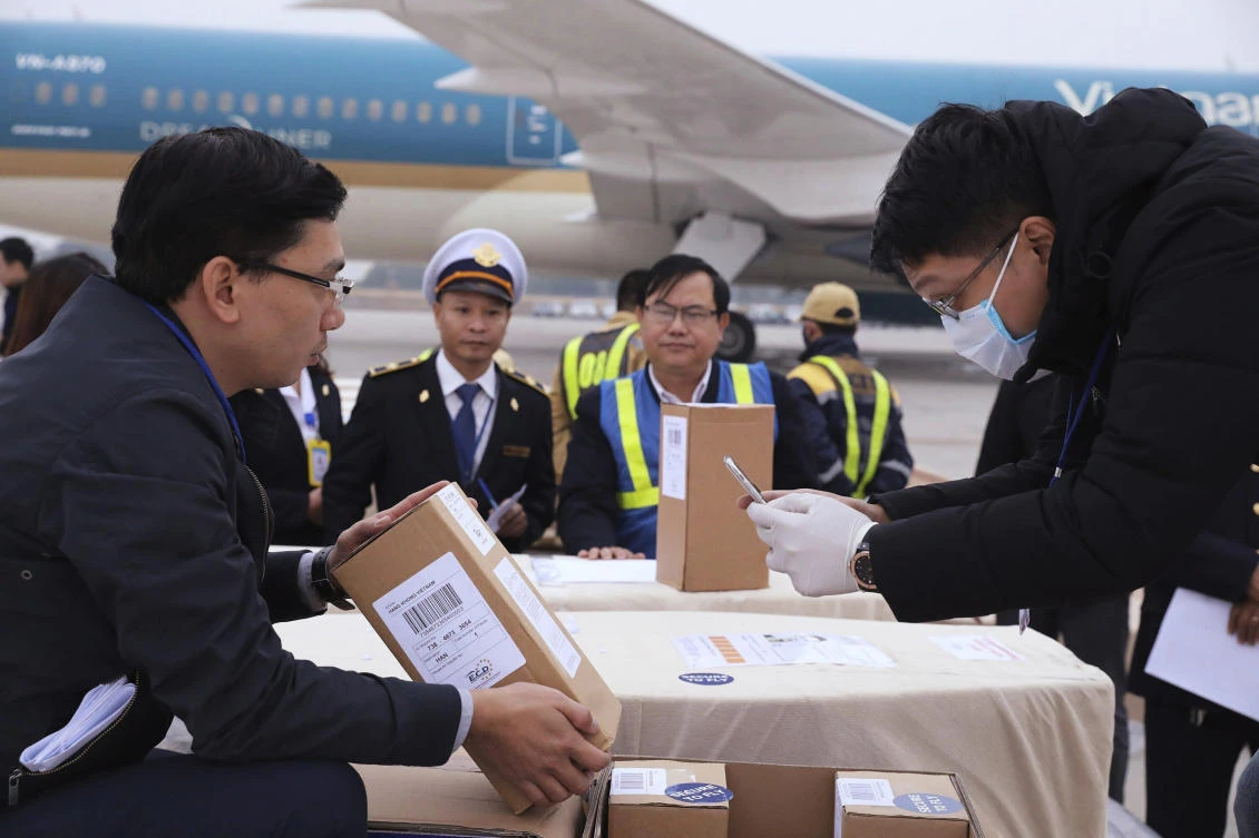 Vietnamese officials examine a carton box with human remains at the tarmac of the Noi Bai airport in Hanoi on Saturday, Nov. 30, 2019. (VNA via AP)