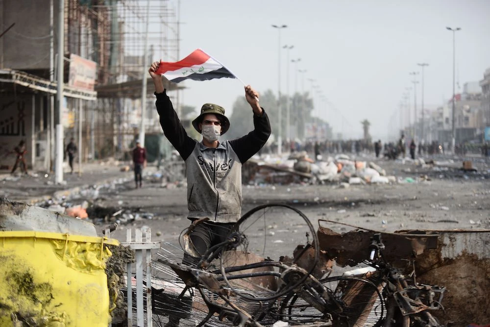 An Iraqi demonstrator carries the national flag in Najaf on Sunday, where protests continued to rage. (Reuters)