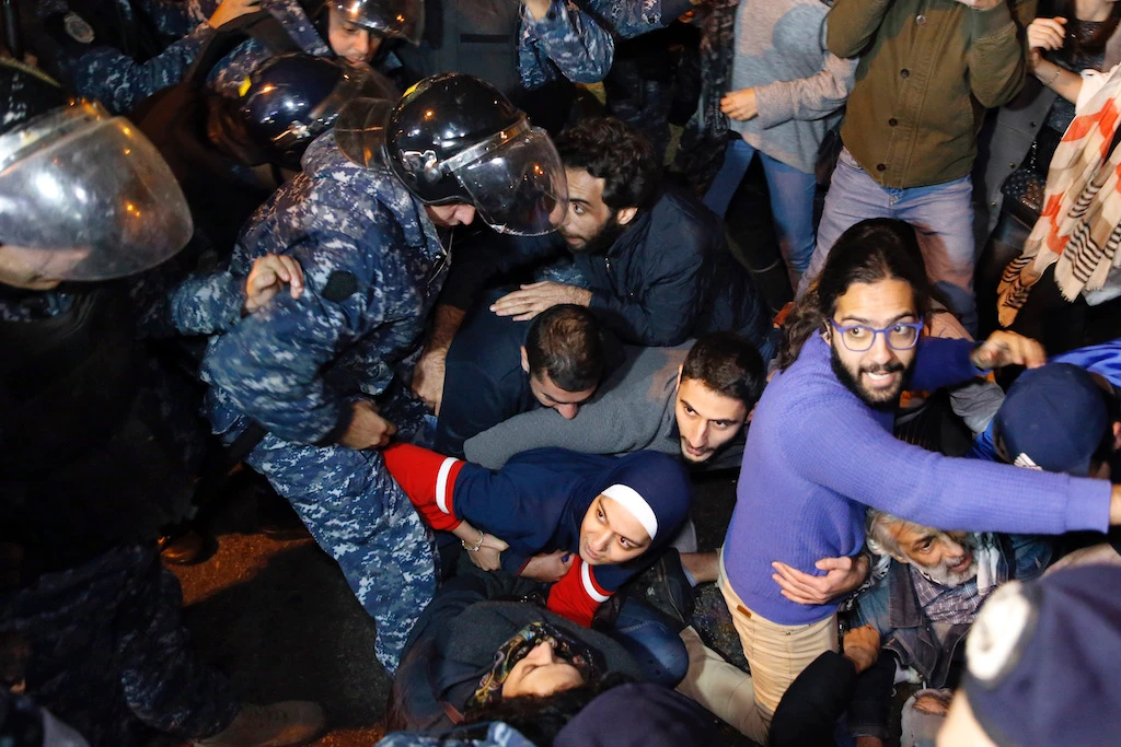 Anti-government protesters lie on a road, as they scream and hold each others while riot police try to remove them and open the road, in Beirut, Lebanon, Wednesday, Dec. 4, 2019. (AP)