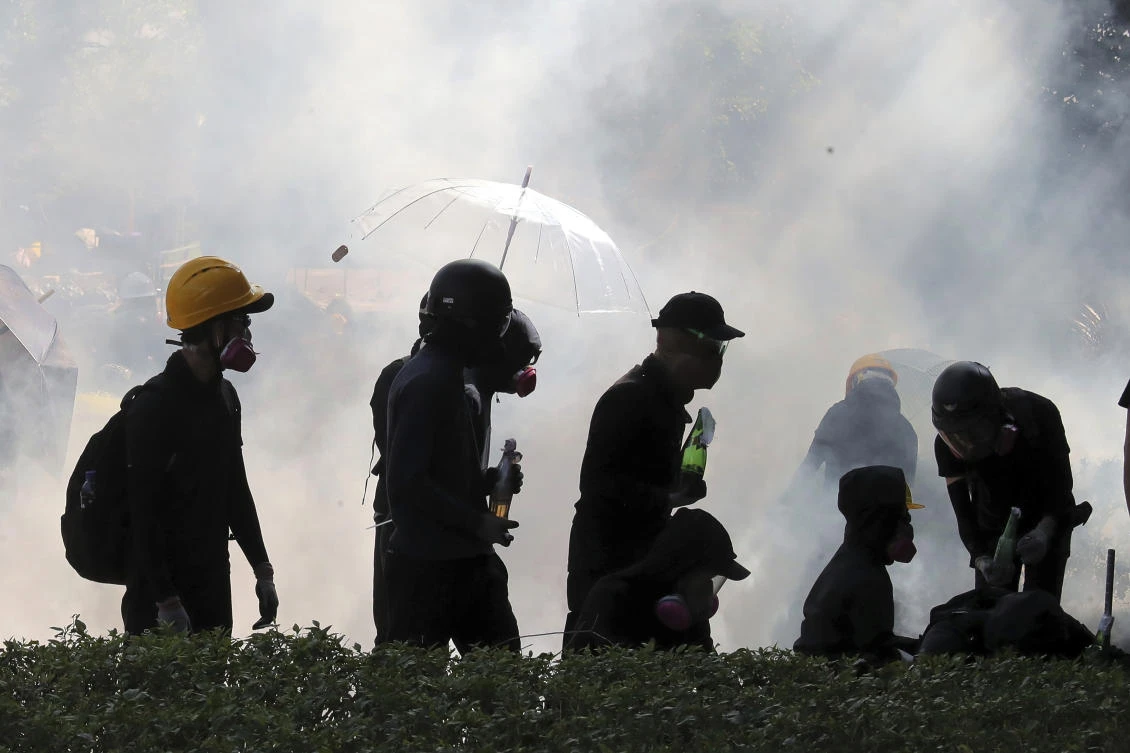 In this Sunday, Nov. 17, 2019, file photo, pro-democracy protestors react as police fire tear gas at Hong Kong Polytechnic University in Hong Kong. (AP)